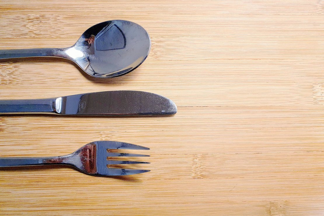 Löffel, Messern und Gabel auf Holzplatte